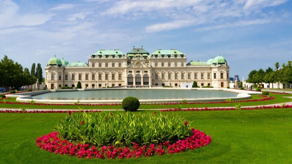 Best cities to visit in Europe: The magnificent Belvedere Palace in Vienna, Austria, with its Baroque architecture reflected in a serene pond surrounded by manicured gardens.
